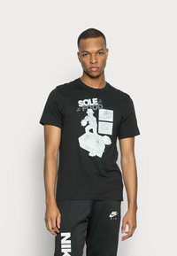Sort bomulds t-shirt med grafisk tryk med ordene "SOLE FOOD" og illustrative designs, rund halsudskæring og korte ærmer.