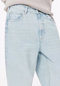 Lichtblauwe denim jeans met een recht model, klassieke zakken, subtiele stikdetails en een vervaagde wastextuur.