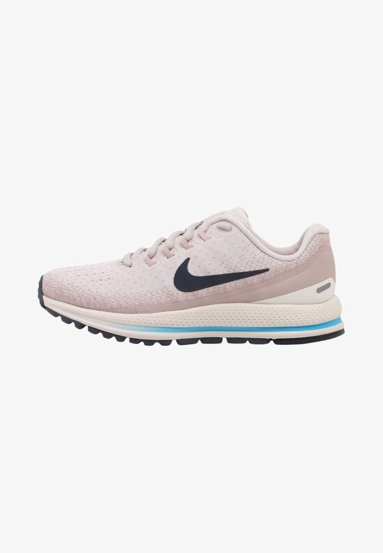 Chaussure de course Nike rose clair avec logo Swoosh noir, semelle rembourrée avec bande bleue et semelle extérieure noire crantée.