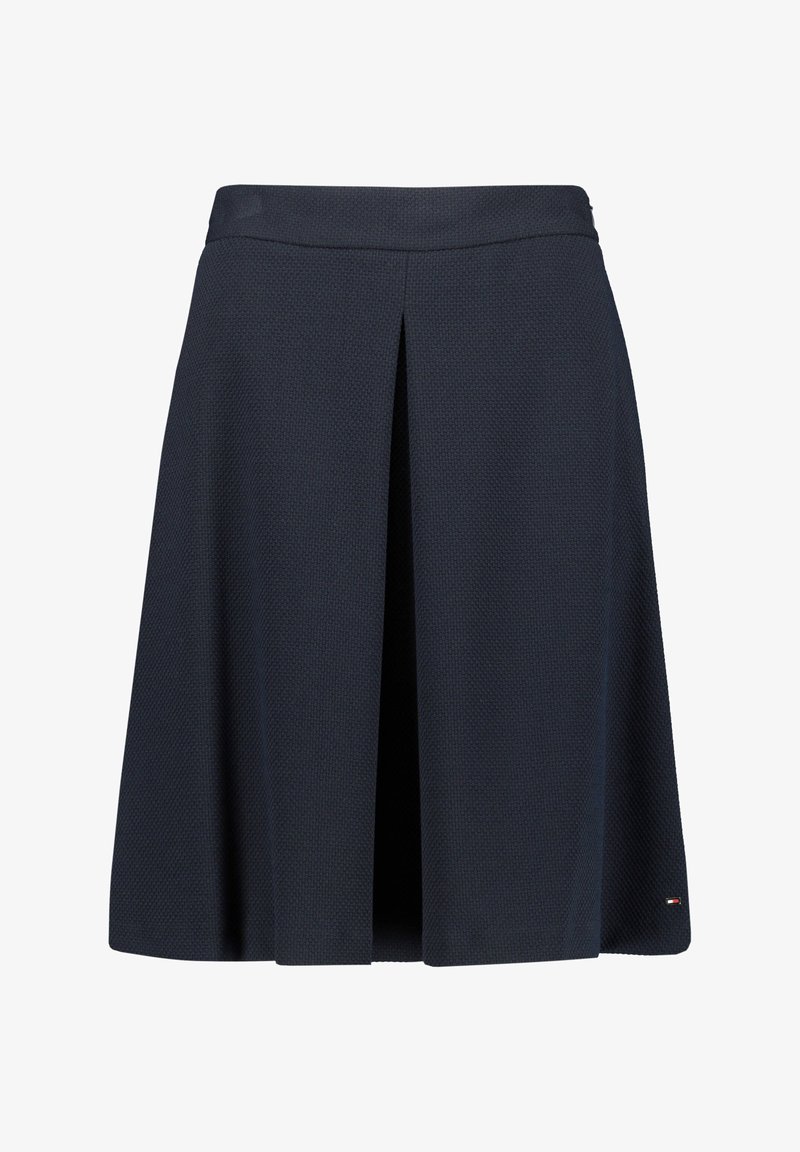 Tummansininen polviin asti ulottuva hame, jossa on edessä keskellä laskos ja hienovarainen tekstiilikuosi, pieni logo helman oikealla puolella.