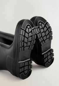 Mustad kummisaapad tekstuurse tallaga. Tallas on sügav mustriga muster haardumise jaoks, sile, kumer kand ja ümar nina.