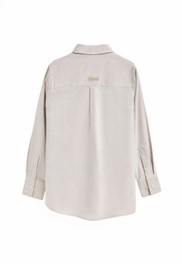 Jasno-beżowa koszula zapinana na guziki z kołnierzykiem, długimi rękawami i centralnym plisem z tyłu. Wykonana z gładkiego materiału o delikatnym połysku.