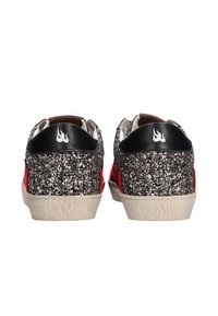 Un par de zapatillas cubiertas de purpurina con pestañas en el talón negras que presentan logotipos de llamas blancas y acentos rojos en los laterales, suelas grabadas con "GAMIN".