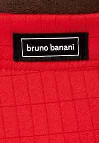 Rød stof med mønster af firkanter og et elastisk bånd, prydet med en sort label med hvid tekst, der står "bruno banani."
