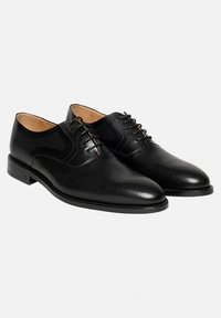 Schwarze Lederschuhe mit durchbrochenem Design, glatter Oberfläche, runder Zehenform und Schnürsenkeln. Mit einem niedrigen Absatz und dezenten Steppnähten.