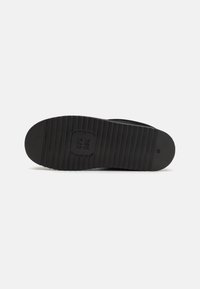 Suela de zapato de goma negra con textura estriada y detalle de marca circular. Talla indicada como 42. Acabado liso y forma de punta redondeada.