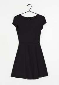Robe noire à manches courtes avec un corsage ajusté, une jupe évasée et un subtil motif texturé. Suspendue à un cintre en métal noir sur un fond blanc.