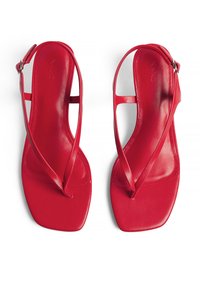 Red leather sandals with thin, crisscross straps, a square toe design, and a smooth texture. Adjustable ankle strap with a buckle detail.