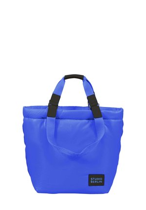 Blå polstret tote bag med rektangulær form, utstyrt med svart maskinvare, to øvre hanke, og et merke foran. Holdbart materiale.