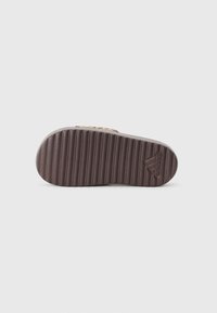 Brown rubber shoe sole with ridged texture and adidas logo, featuring a rounded shape and smooth finish.