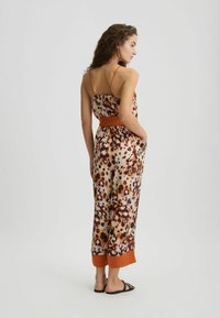 Geprinte jumpsuit met een luipaardprint, voorzien van dunne bandjes, een oranje riem en contrasterende manchetten aan de zoom. Soepele, lichte stof.