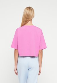 Κοντομάνικη ροζ κοντή μπλούζα με στρογγυλή λαιμόκοψη και λείο ύφασμα. Ορατή ραφή στο τελείωμα και στις άκρες των μανικιών.