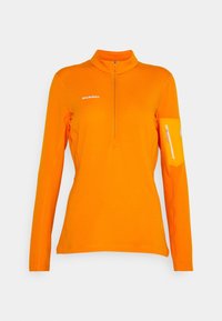 Haut orange à manches longues avec un col demi-fermeture éclair, doté d'une poche sur le bras gauche et d'un tissu texturé, marqué du logo "MAMMUT" en blanc.