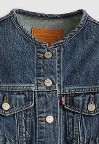 Denimjakke med blå vask, med rund hals, kobberfarget søm, sølvfarget beslag og to frontlommer med knappelukking.