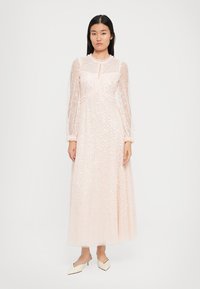 Maxime dress in soft pink mesh with long sheer sleeves. Já na tsarin keyhole da kuma kayan haɗi mai laushi a ko'ina.