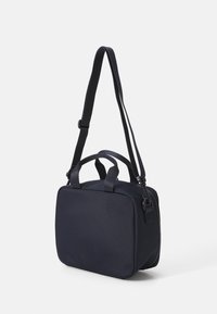 Sac en tissu bleu marine de forme rectangulaire, doté de deux poignées et d'une bandoulière réglable, surface texturée et fermeture éclair.