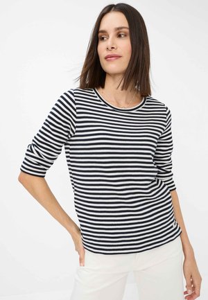 Gestreiftes Langarm-Oberteil in Marineblau und Weiß aus strukturiertem Stoff mit Rundhalsausschnitt, kombiniert mit weißen Hosen. Minimalistisches Design mit 3/4-Ärmeln.