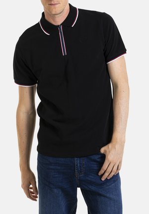 Polo noir avec un col zippé, présentant des accents de col et de manches rayés rouges et blancs, et un tissu texturé.