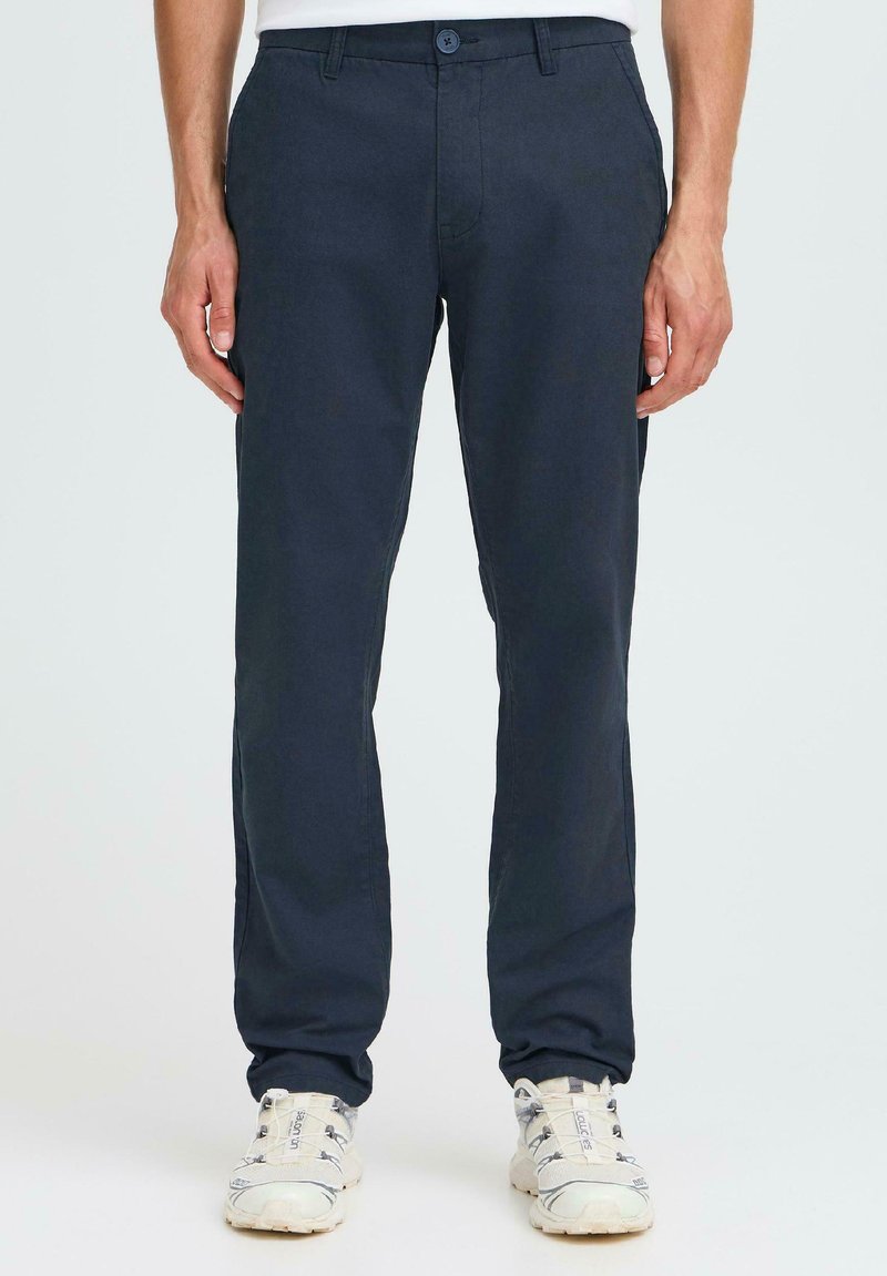 Pantalons marine en tissu léger, dotés d'une fermeture à bouton et de poches avant. Design à jambe droite avec une texture lisse.