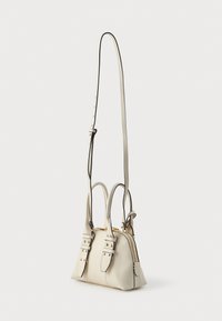 Bolsa de couro branca com fecho dourado, duas alças e uma alça ajustável. Apresenta rebordos em preto contrastante e elegantes detalhes com tachas.