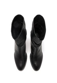 Botines de cuero negro con una textura suave, forma alargada y diseño fruncido en la parte superior. Punta puntiaguda. Sin herrajes visibles.