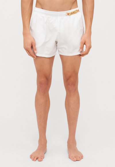 Shorts de bain blancs avec une taille élastique et un accent logo doré à l'avant. Tissu lisse et léger, longueur mi-cuisse.