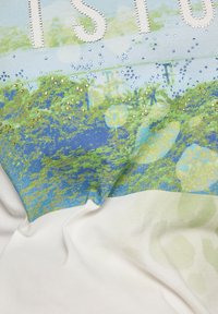 Lightweight, short-sleeve shirt with a blue and green abstract pattern, adorned with gold and blue rhinestones, featuring a soft, smooth texture.