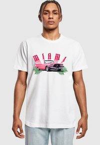 White cotton t-shirt featuring a colorful "MIAMI" graphic, a pink convertible car, and palm leaves, with a relaxed fit and crew neck design.