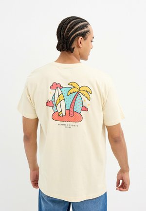 Camiseta de algodón beige con un estampado gráfico de palmeras, tablas de surf y nubes en colores brillantes, con el texto "VIBRACIONES DE NOCHES DE VERANO" en la parte inferior.