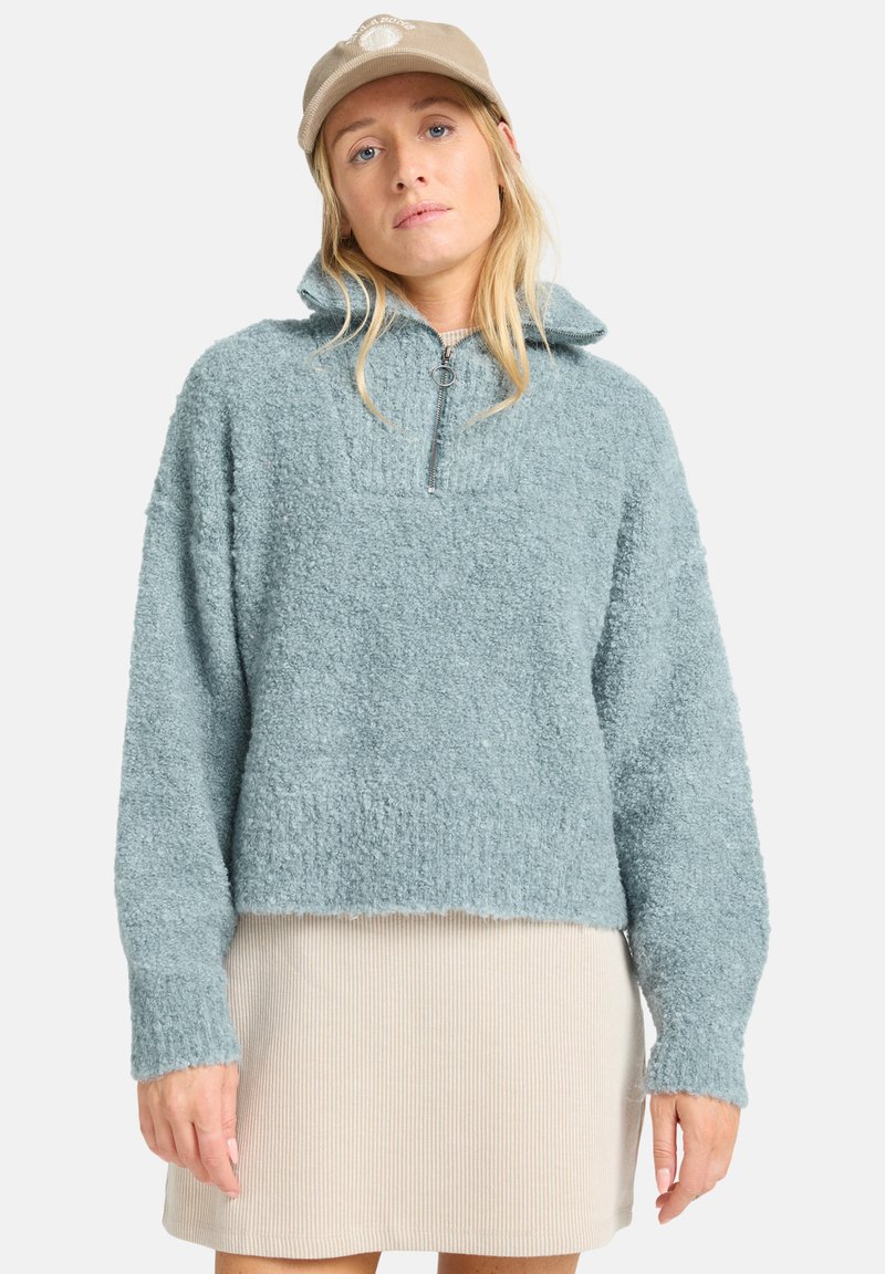 Pullover azzurro chiaro in pile con zip a quarti, caratterizzato da una finitura testurizzata e una vestibilità rilassata, abbinato a una gonna beige a coste.