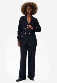 Zwarte dubbelzijdige blazer met gouden knopen, voorzien van flapzakken en een getailleerde pasvorm, gecombineerd met bijpassende wijde broek.