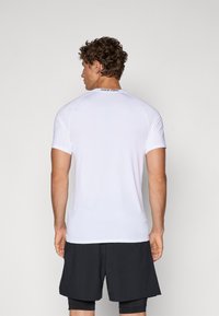 Weißes Nike Pro Sportshirt mit kurzen Ärmeln, glatter Textur und tailliertem Design. Schwarzes Logo am Hals, kombiniert mit schwarzen Shorts.