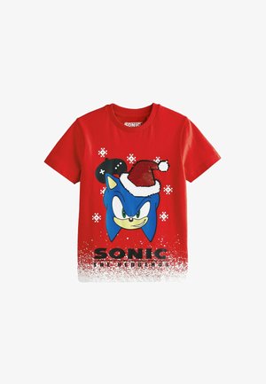 Czerwona bawełniana koszulka z niebieską postacią w czapce świątecznej, śnieżnymi akcentami i napisem "SONIC THE HEDGEHOG" na dole.