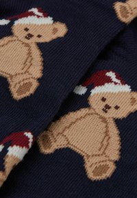 Strikket navy sweater med brune teddy-bear designs iført røde og hvide julestrithuer; blød tekstur med farverige mønstre.