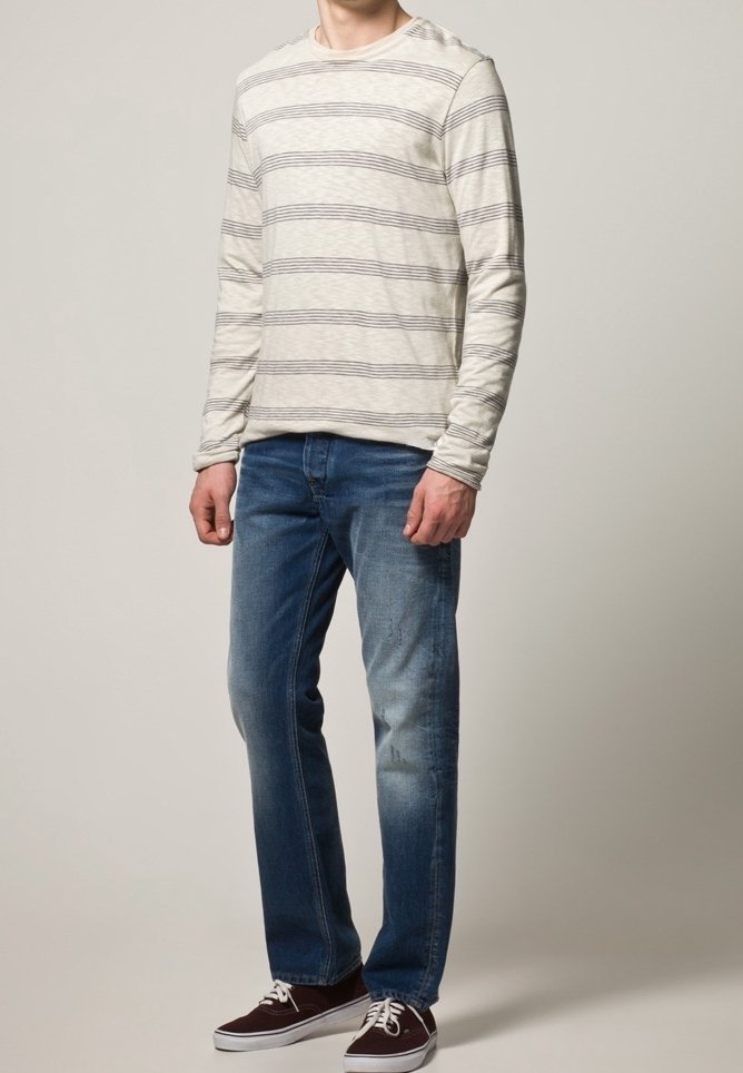 Pitkähihaisen, kerma värisen paidan tummat vaakasuorat raidat, yhdistettynä sinisiin farkkuihin. Farkuissa on vaaleaa kulumaa ja ne ovat suorat. Ruskeat lenkkarit.