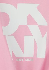 Roze katoenen t-shirt met grote witte blokletters die "DKNY" spellen, met daaronder in kleinere tekst "EST. 1989". Soepele textuur, casual design.