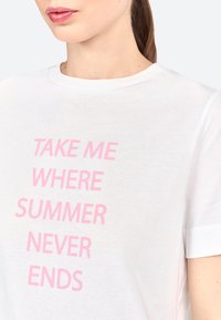 Witte katoenen t-shirt met lichtroze tekst "NEEM ME MEE NAAR EEN ZOMER DIE NOOIT EINDIGT." Korte mouwen en een ronde hals.