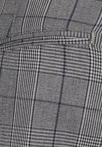 Vävt tyg med ett grått och marinblått rutmönster. Har framträdande rutor och fina linjer, med en mjuk textur och subtil glans.