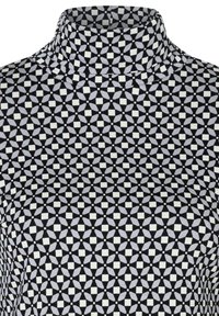 Black and white patterned high-neck top featuring geometric designs with squares and curved shapes, made from a smooth fabric.