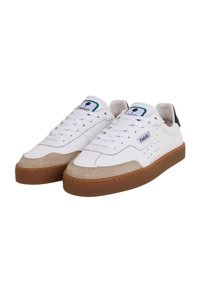 White leather sneakers with beige suede accents and a brown rubber sole. Features include perforations, laces, and a logo patch on the tongue.
