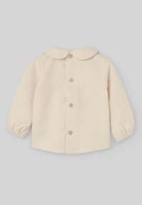 Chemise beige à manches longues avec un col arrondi, une fermeture à boutons et des poignets froncés. Tissu texturé avec un motif subtil.