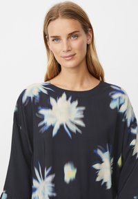 Sort blomsterkjole med løs pasform, med blå og hvide blomsterprint. Blødt stof, rund halsudskæring og afslappede ærmer.