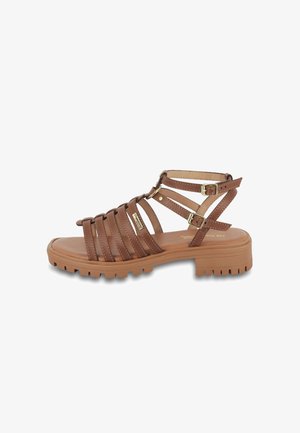 Brown strappy sandals with a chunky rubber sole, multi-strap design, and adjustable buckles, featuring a smooth texture and subtle stitching.
