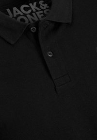 Schwarzes Polohemd mit klassischem Kragen, zwei schwarzen Knöpfen und strukturiertem Stoff. Das Etikett im Kragen trägt die Aufschrift "JACK & JONES". Schlichtes Design.