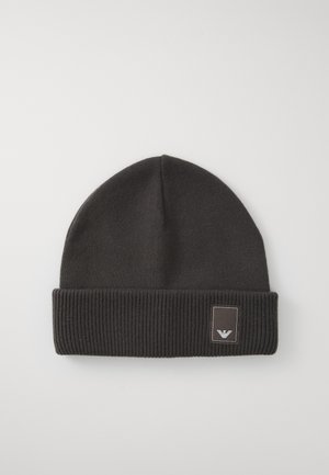Bonnet en tricot noir avec un revers côtelé. Présente un petit patch logo rectangulaire avec un emblème stylisé à l'avant. Texture lisse.