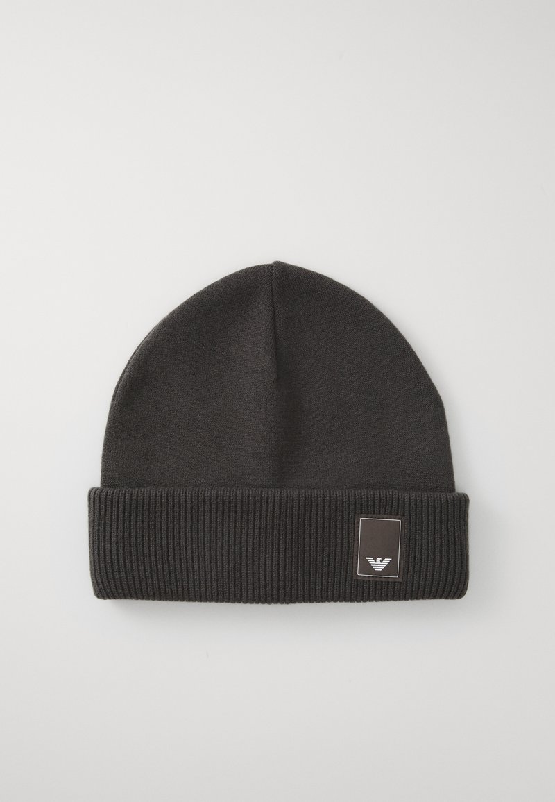 Black knit beanie with a ribbed cuff. Features a small rectangular logo patch with a stylized emblem on the front. Smooth texture.