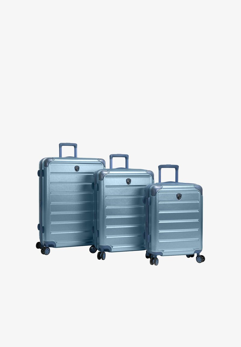 Trois valises rigides bleues de tailles variées avec poignées rétractables et quatre roues doubles pivotantes chacune.