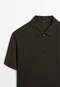 Polo shirt corto a maniche corte di colore marrone scuro, con colletto rigido, chiusura frontale con zip e texture del tessuto liscia.