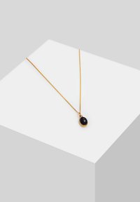 Goldkettchen-Halskette mit einem schwarzen ovalen Anhänger mit polierter Oberfläche. Einfaches Design mit zarter und glatter Textur.