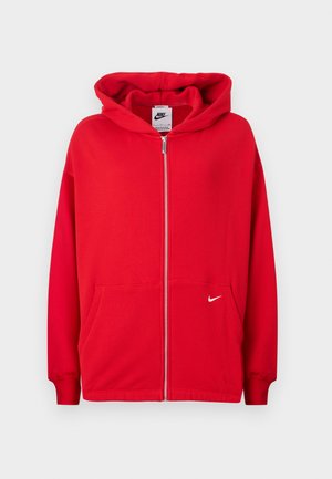 Sarkans zip-up džemperis, kas izgatavots no mīksta auduma. Iespējo kangaru kabatu, ribotas piedurknes un baltu Nike logotipu kreisajā krūtī.